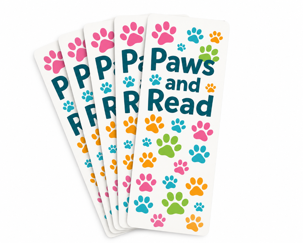 Five white book bookmarks fanned out on a white background, printed with the words 'Paws and Read' in dark teal and decorated with colorful dog paw prints in pink, blue, green, and orange.