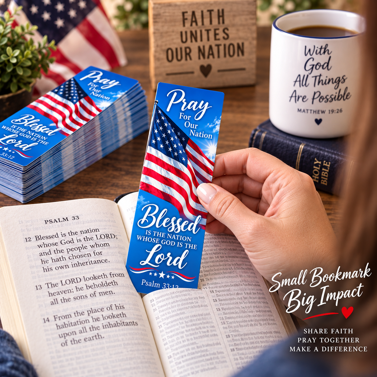 A hand holds a blue and red American flag bookmark shaped like a Bible page, with the text 'Pray For Our Nation' and 'Blessed Is The Nation Whose God Is The Lord.' Other matching bookmarks, an open Bible, a mug, and a wooden sign reading 'FAITH UNITES OUR NATION' are visible on a tabletop.