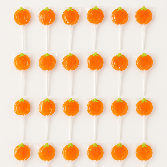 Pumpkin-shaped lollipops on white sticks arranged in rows. Thanksgiving candy.