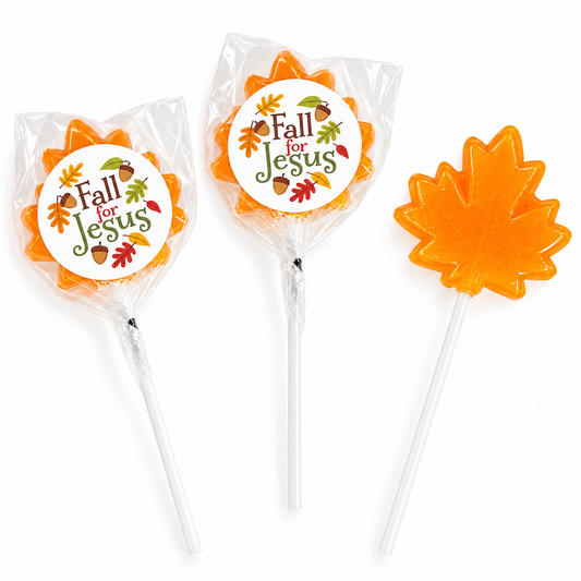 Three orange autumn-themed lollipops on a white background: two wrapped in clear cellophane with round white labels reading 'Fall for Jesus,' and one unwrapped showing a bright orange maple leaf-shaped candy.