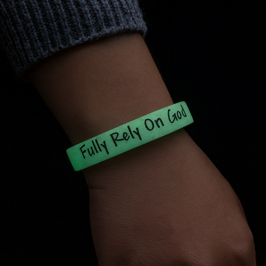 Green wristband with 'Fully Rely On God' text on a wrist against a dark background