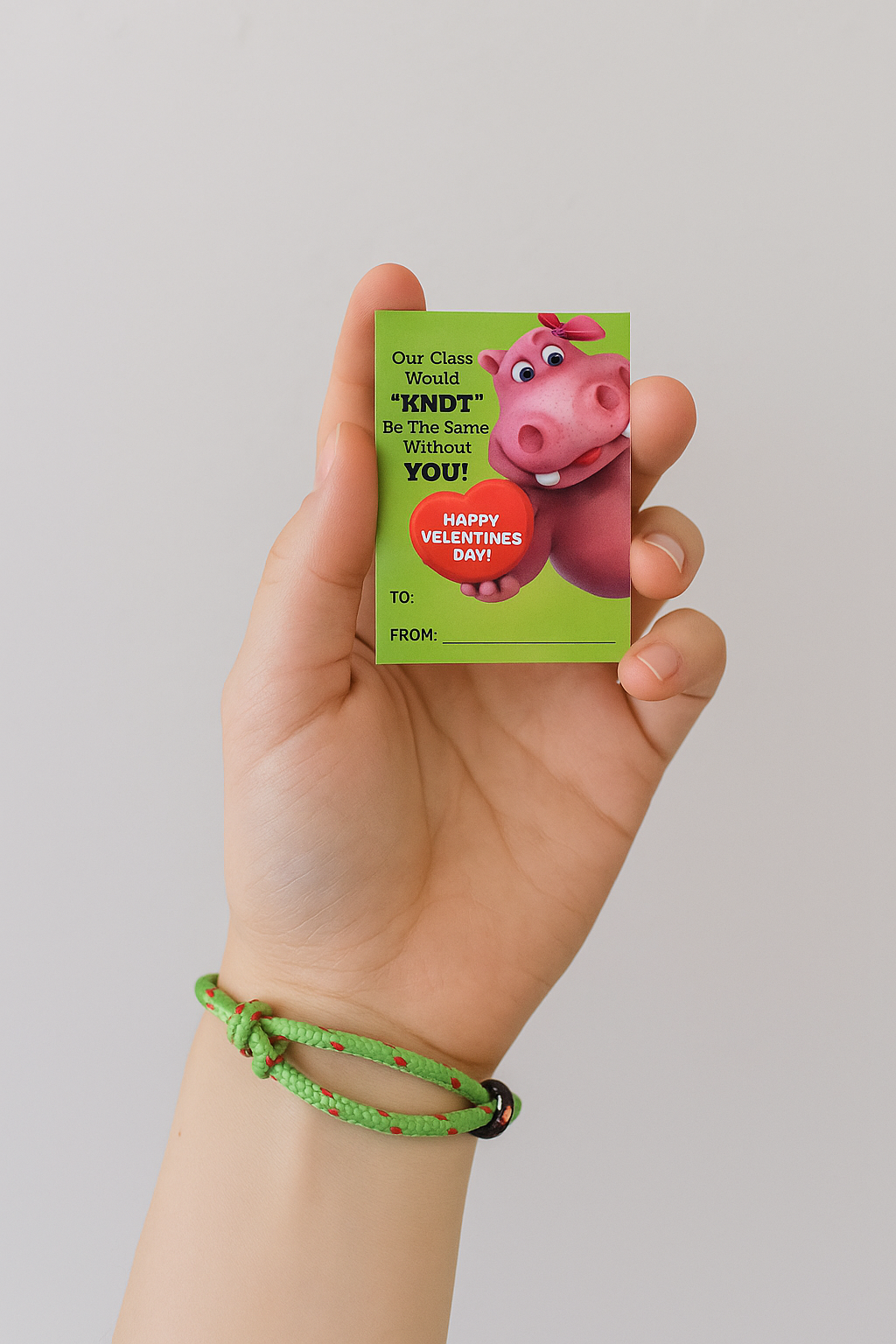 Hand holding a Valentine's Day card with a cartoon pig design on a plain background