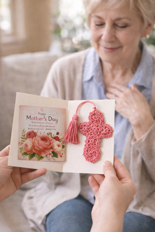 Person holding a 'Happy Mother's Day' card with a pink crocheted cross and tassel, given to an older woman.