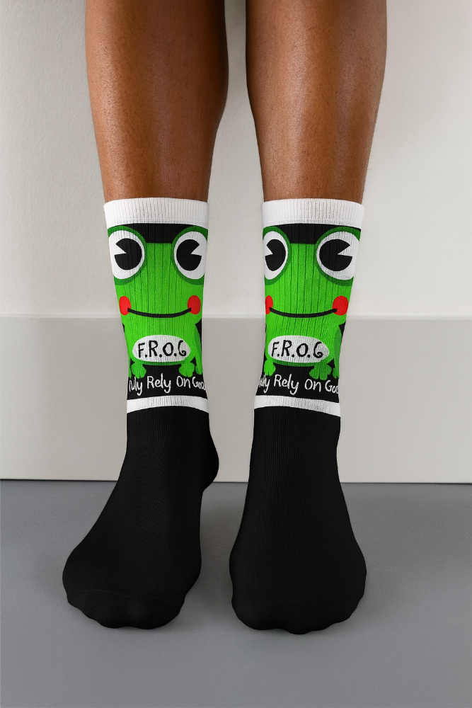 Person wearing black socks with green frog design and white accents on a neutral background