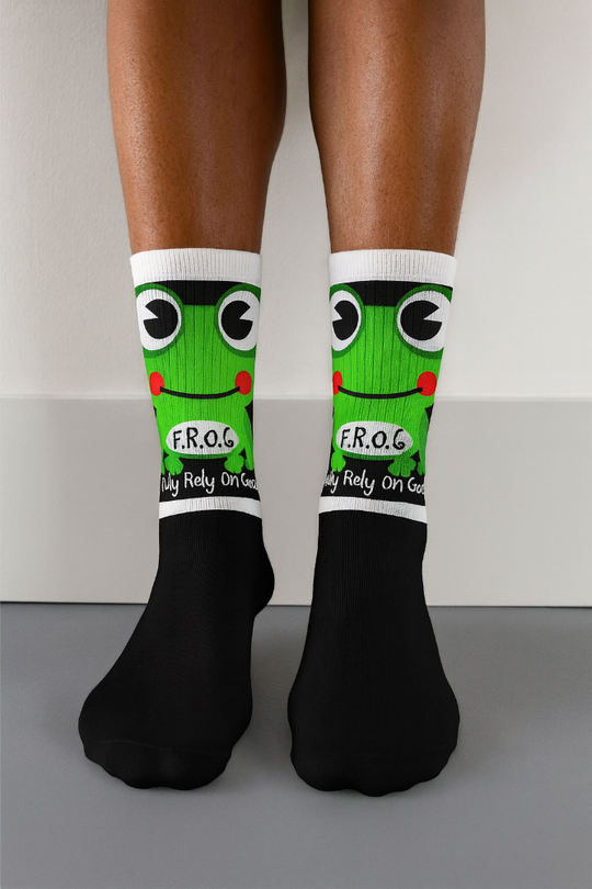 Person wearing black socks with green frog design and white accents on a neutral background