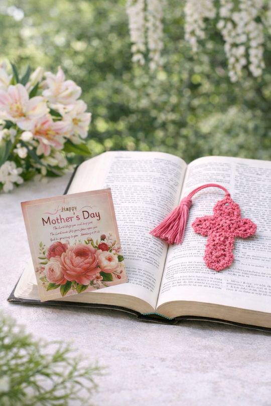 Open book with a 'Happy Mother's Day' card and pink cross bookmark on a natural background.