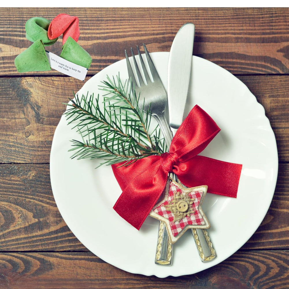 Decorative Christmas place setting with a red ribbon, silverware, and a star-shaped ornament on a wooden table.