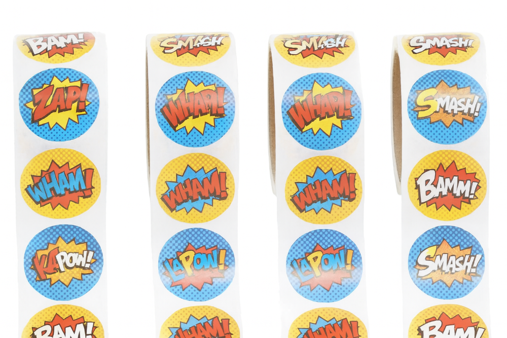 Rolls of superhero-themed stickers with words like 'BAM!', 'WHAM!', and 'SMASH!' on a white background.