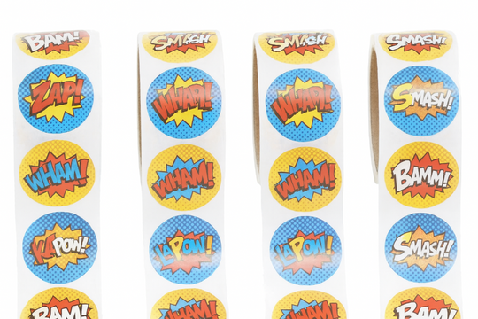 Rolls of superhero-themed stickers with words like 'BAM!', 'WHAM!', and 'SMASH!' on a white background.